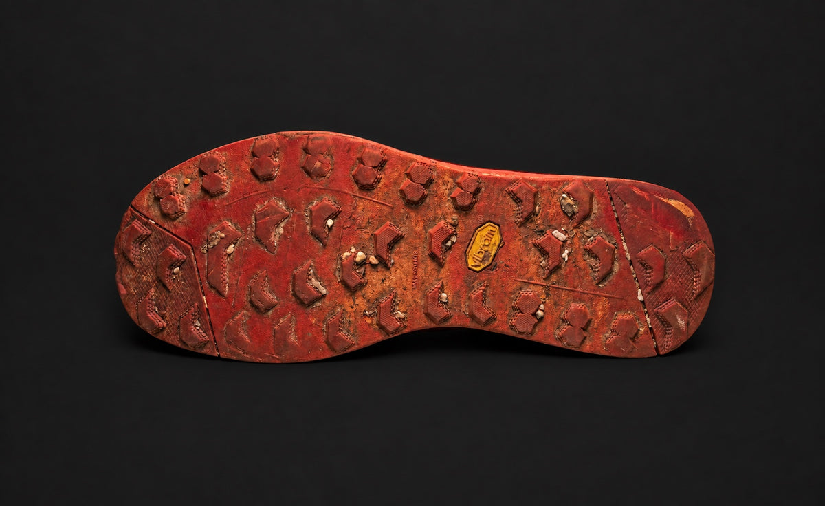 Entire red-earth marked Vibram outsole on a dark charcoal background